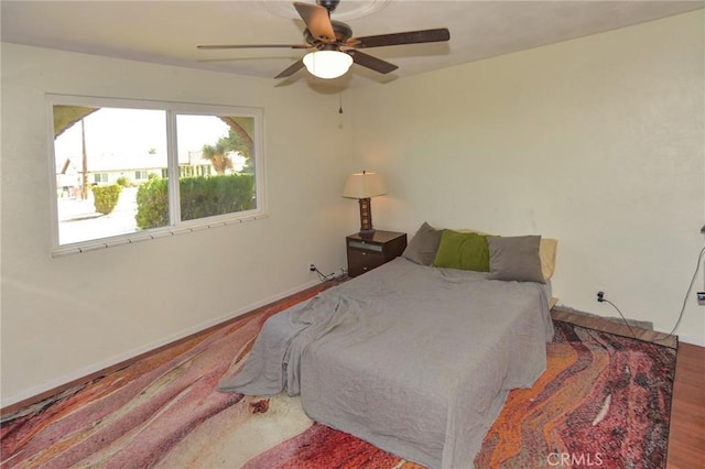 bedroom with ceiling fan, baseboards, and wood finished floors