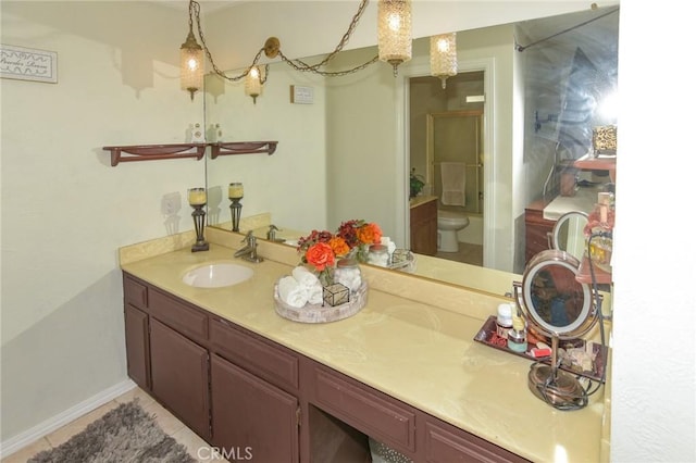 bathroom with toilet, a shower with shower door, baseboards, and vanity