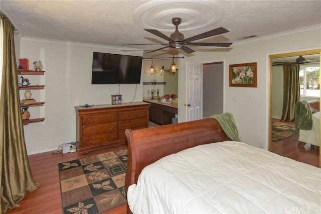 bedroom featuring a textured ceiling, visible vents, wood finished floors, and ornamental molding