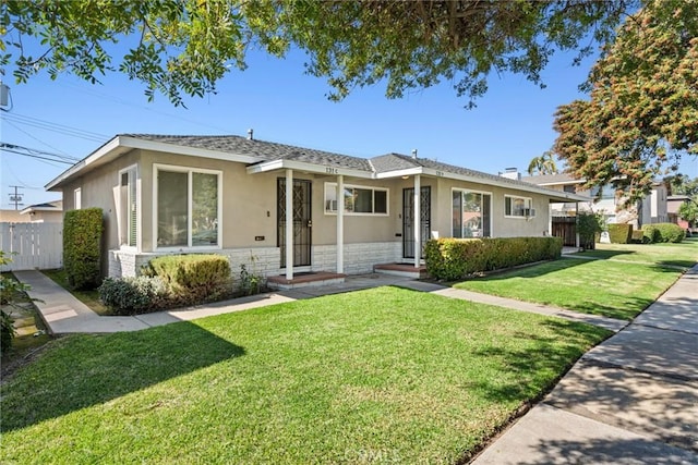 view of front of home featuring stone siding, fence, a front lawn, and stucco siding