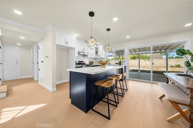 kitchen featuring a center island, stainless steel stove, light wood-style floors, white cabinets, and under cabinet range hood