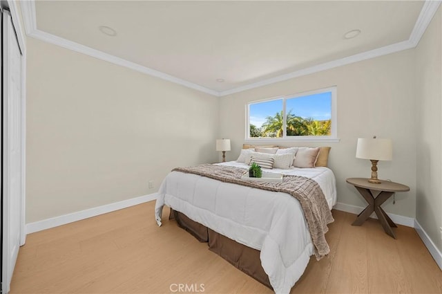 bedroom featuring baseboards, crown molding, and light wood finished floors