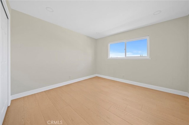 spare room featuring light wood-type flooring and baseboards