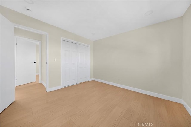 unfurnished bedroom with a closet, light wood-type flooring, and baseboards