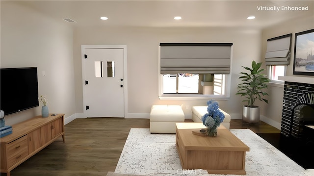 living area featuring recessed lighting, visible vents, a tiled fireplace, and wood finished floors