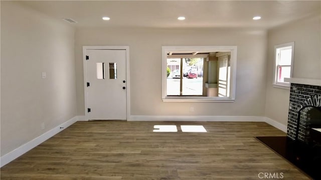 foyer with a fireplace, baseboards, a wealth of natural light, and wood finished floors