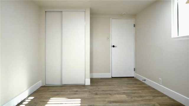 unfurnished bedroom with a closet, baseboards, and wood finished floors