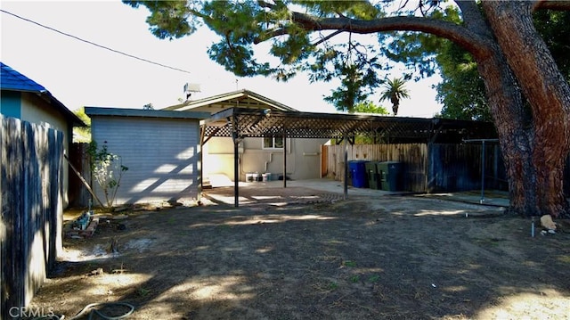 rear view of property featuring a patio, an outdoor structure, and fence