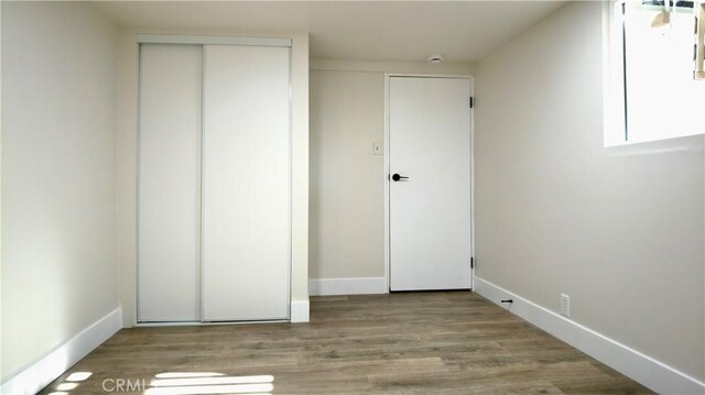unfurnished bedroom featuring a closet, baseboards, and wood finished floors