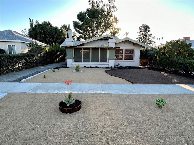 view of front of home featuring driveway, a sunroom, and stucco siding