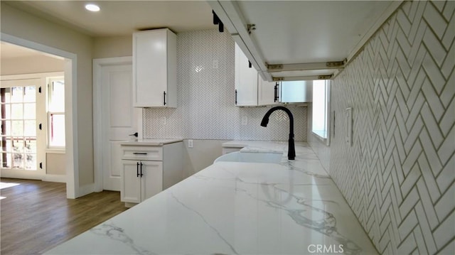 kitchen with tasteful backsplash, white cabinets, wood finished floors, light stone countertops, and recessed lighting