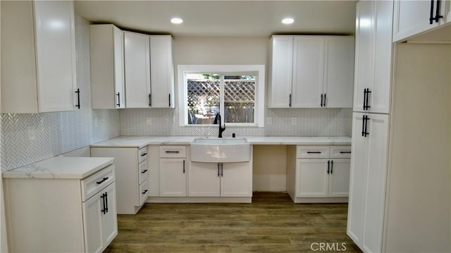 kitchen with white cabinets, a sink, backsplash, and wood finished floors