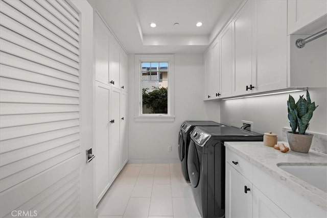 laundry area with light tile patterned flooring, washing machine and dryer, recessed lighting, a sink, and cabinet space