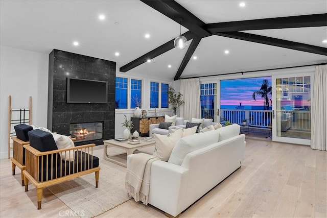 living area featuring a fireplace, light wood-style flooring, and lofted ceiling with beams