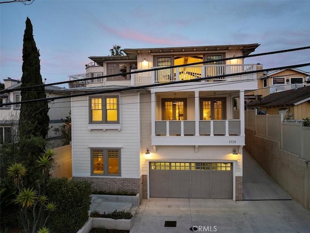 view of front facade with brick siding, concrete driveway, fence, a balcony, and a garage