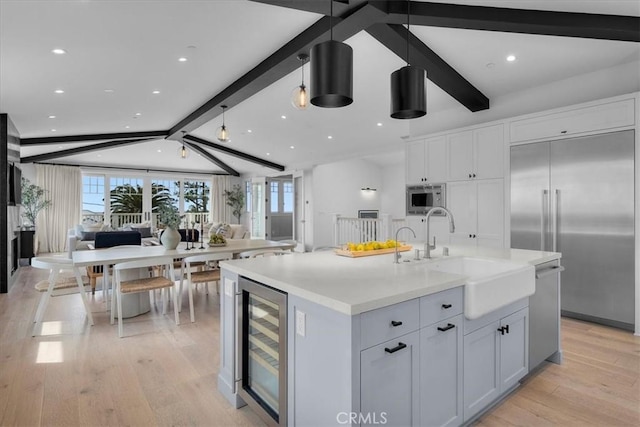 kitchen with wine cooler, open floor plan, built in appliances, vaulted ceiling with beams, and a sink