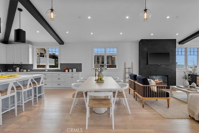 dining space featuring light wood-type flooring, plenty of natural light, and beamed ceiling