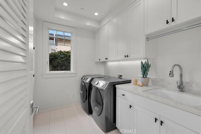 clothes washing area featuring cabinet space, baseboards, washing machine and clothes dryer, a sink, and recessed lighting