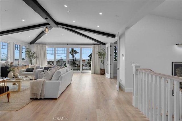 living room featuring light wood-type flooring, vaulted ceiling with beams, and baseboards