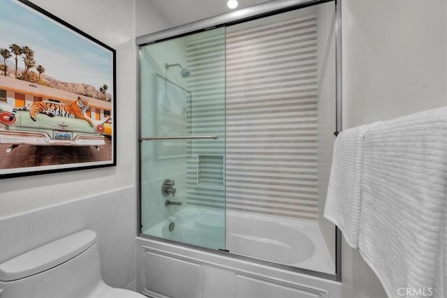 bathroom featuring shower / bath combination with glass door, tile walls, and toilet