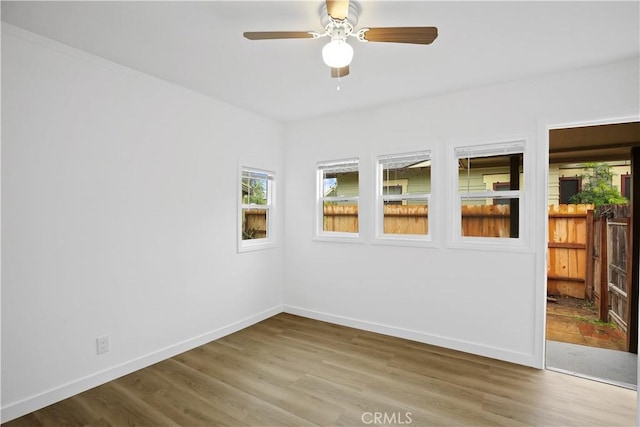 unfurnished room featuring ceiling fan, wood finished floors, and baseboards