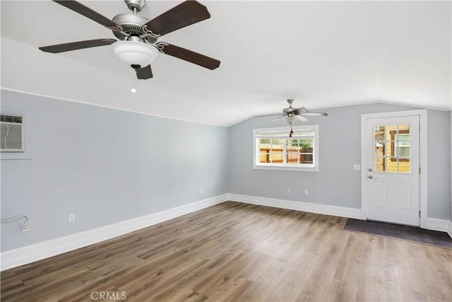 unfurnished living room featuring vaulted ceiling, a wall mounted AC, baseboards, and wood finished floors