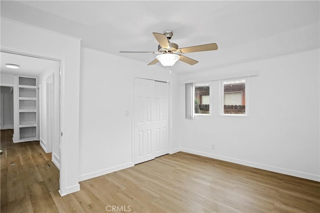 unfurnished bedroom featuring ceiling fan, a closet, wood finished floors, and baseboards