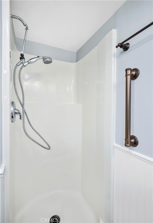 bathroom featuring a shower and wainscoting