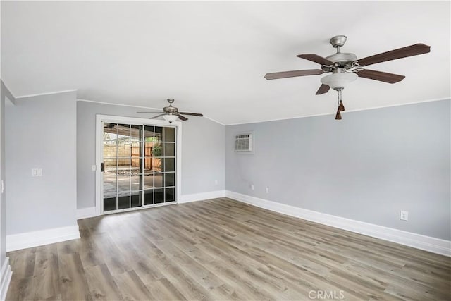 spare room featuring ceiling fan, a wall mounted AC, wood finished floors, and baseboards