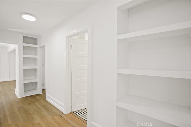 corridor with light wood finished floors and baseboards