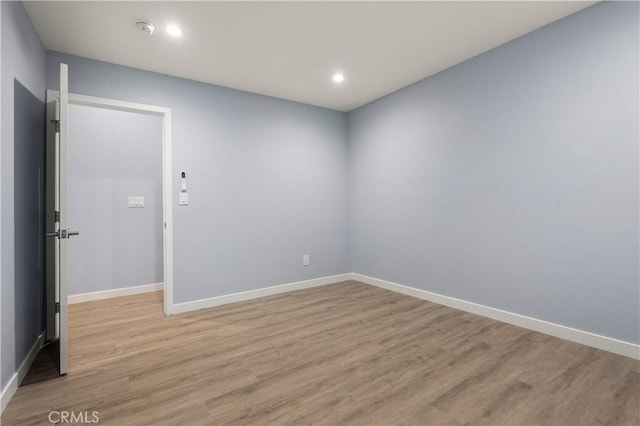 empty room with light wood finished floors, recessed lighting, and baseboards