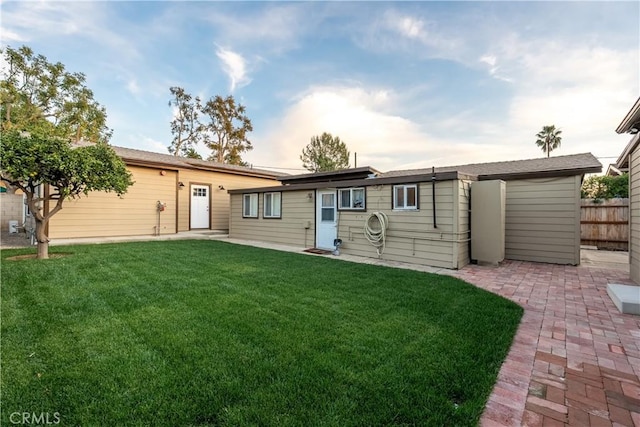 rear view of house with a yard, fence, and a patio