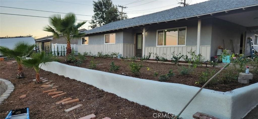 exterior space featuring a shingled roof and stucco siding