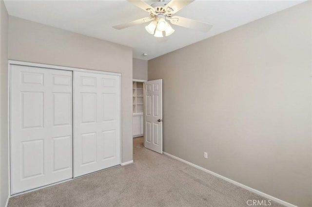 unfurnished bedroom featuring a ceiling fan, baseboards, a closet, and light colored carpet