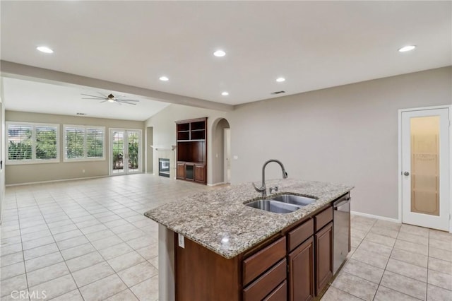 kitchen with light tile patterned floors, recessed lighting, a sink, stainless steel dishwasher, and an island with sink