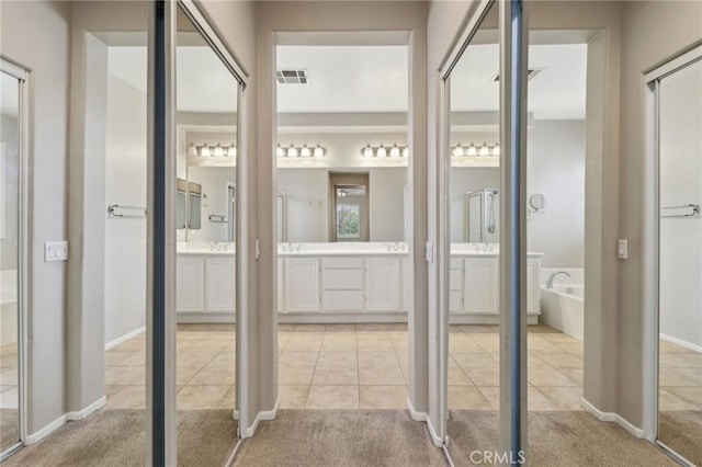 full bathroom with two vanities, tile patterned flooring, visible vents, and a garden tub