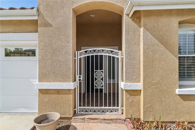 property entrance with a garage and stucco siding