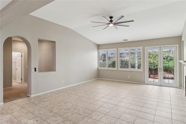 empty room with arched walkways, light tile patterned flooring, lofted ceiling, and visible vents