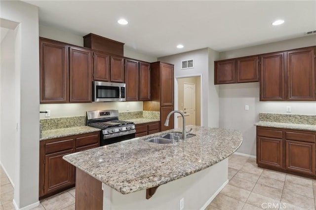 kitchen featuring light stone counters, recessed lighting, stainless steel appliances, a sink, and visible vents