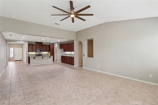 unfurnished living room featuring ceiling fan, arched walkways, visible vents, baseboards, and vaulted ceiling