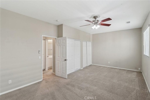 unfurnished bedroom featuring carpet floors, two closets, visible vents, and baseboards