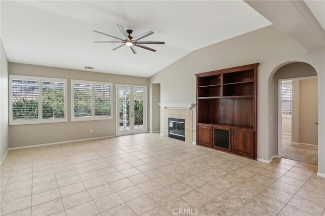 unfurnished living room featuring light tile patterned floors, visible vents, a ceiling fan, vaulted ceiling, and a tiled fireplace