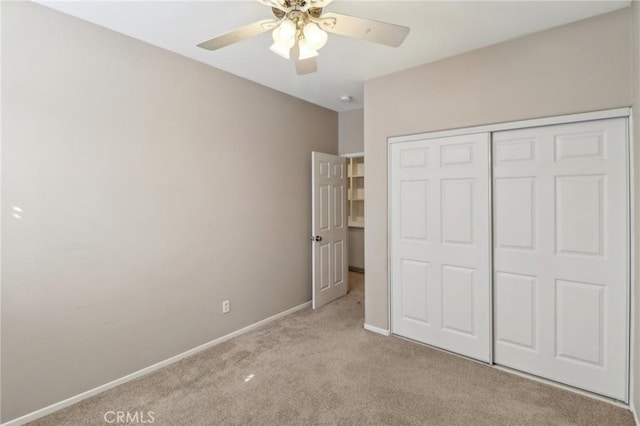 unfurnished bedroom with a closet, carpet flooring, a ceiling fan, and baseboards