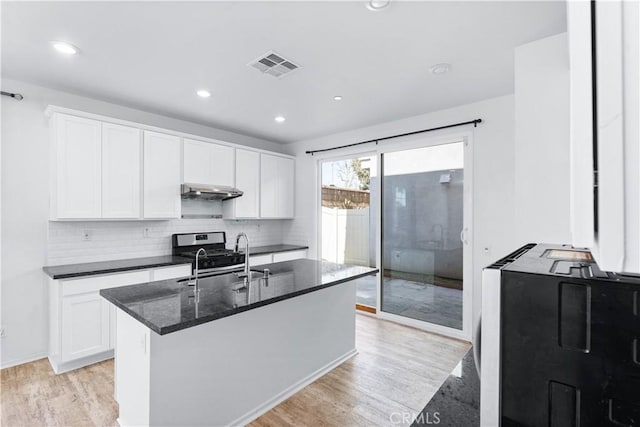 kitchen featuring light wood-type flooring, white cabinetry, visible vents, and a sink