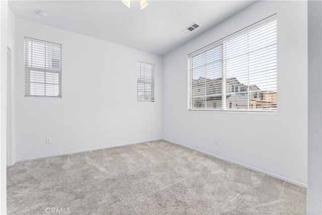 carpeted spare room featuring visible vents and baseboards