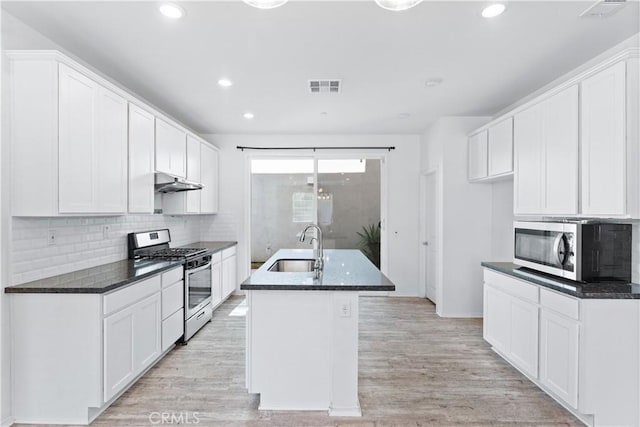 kitchen with light wood finished floors, visible vents, appliances with stainless steel finishes, a sink, and under cabinet range hood