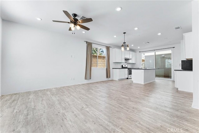 unfurnished living room featuring light wood finished floors, baseboards, a ceiling fan, a sink, and recessed lighting