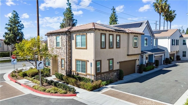 townhome / multi-family property featuring stucco siding, an attached garage, stone siding, driveway, and a tiled roof