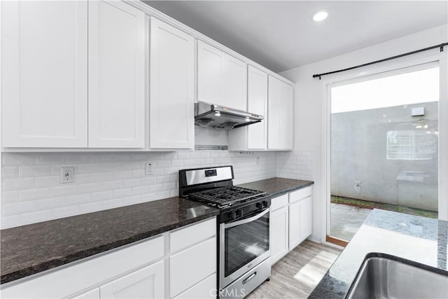 kitchen with white cabinets, stainless steel range with gas stovetop, under cabinet range hood, and backsplash