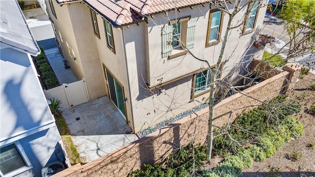 view of side of property featuring a tile roof, fence, and stucco siding